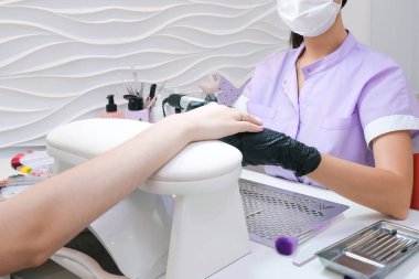 Güzellik Salonu, Manikür. Güzellik salonunda elektrikli makine kullanan profesyonel donanım manikürü. Usta manikür sırasında ojeli elleri kesmek için elektrikli makine kullanıyor.