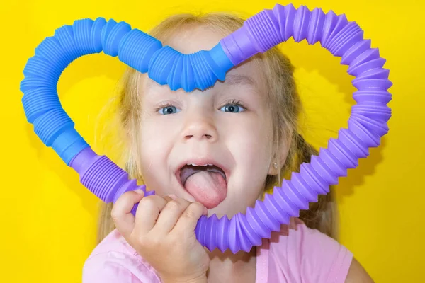 弹出管 从儿童手中弹出的弹簧管中取出抗压感官塑料玩具 快乐的小女孩在玩玩具小提琴管 2021年的趋势 黄色背景 — 图库照片