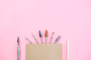 Sterilizasyondan sonra manikür makinesinin yerine takılabilecek eklentiler el işi bir çantada. kopyalama alanı olan pembe bir arkaplan üzerinde