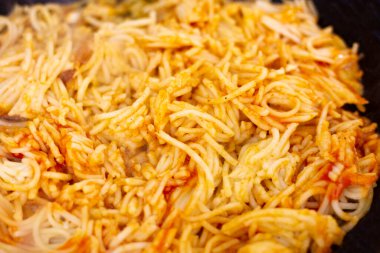 Tavada kızartılmış domatesle karıştırılmış spagetti yakın plan.