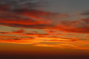 Ufukta deniz kenarında kızıl güneşle gün batımı