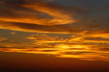 Ufukta deniz kenarında kızıl güneşle gün batımı