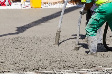 Temel çukurunda hortumlarla çimento karıştıran işçiler