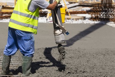 İnşaat halindeki bir binanın temelini çimento borusuyla dolduran bir işçi.