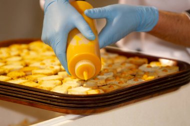 Ellerinde lateks eldivenlerle ördek tüyü damlalarını kare tost parçalarına koyuyorlar.