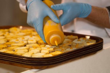 Ellerinde lateks eldivenlerle ördek tüyü damlalarını kare tost parçalarına koyuyorlar.