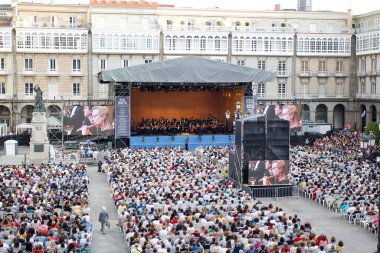 Coruna, İspanya. Seyirciler, 17 Ağustos 2019 'da Plaza de Maria Pita' da düzenlenen Galiçya Senfoni Orkestrası 'nın konserini izliyor, oturuyordu ve ayakta duruyordu.
