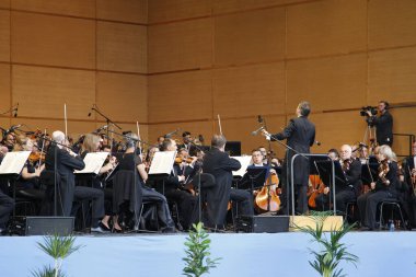 Coruna, İspanya. 17 Ağustos 2019 'da bir açık hava konseri sırasında Galiçya Senfoni Orkestrası müzisyenlerini yöneten orkestra şefi.