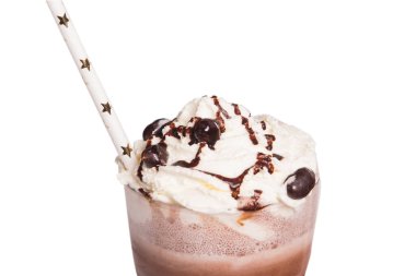 Karamel kremalı çikolatalı milkshake ve beyaz arka planda ışıldayan yıldızlarla süslenmiş samanlı çikolata taneleriyle yakın plan.