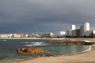 Bir Coruna-İspanya. 7 Şubat 2021 'de fırtınalı bir günde gün batımında şehrin arka planında bulunan Raizor ve Orzan plajlarının genel görüntüsü.