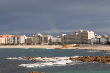 Bir Coruna-İspanya. 7 Şubat 2021 'de fırtınalı bir günde gün batımında şehrin arka planında bulunan Raizor ve Orzan plajlarının genel görüntüsü.