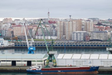 Coruna-İspanya. A Coruna limanının ön planda yük gemisi ve arka planda 18 Şubat 2018 tarihinde şehir ile birlikte balık pazarının hava görüntüsü.