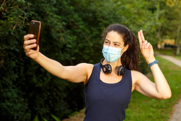 Seorang Wanita Muda Kaukasia Mengenakan Topeng Dengan Headphone Dan Ponsel — Stok Foto