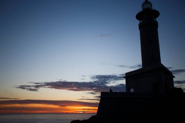 Punta Nariga deniz feneri gün batımında Galiçya 'da deniz kenarındaki kayalık bir dağın tepesinde.
