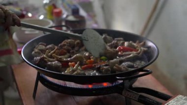 Paella tavasında et ve sebzelerle geleneksel İspanyol yemeklerini karıştıran bir kadının elleri.