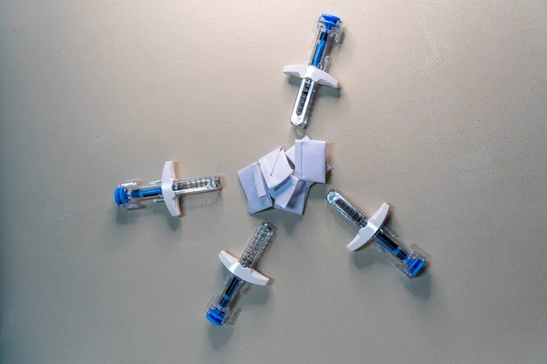 Buruşmuş tıbbi kayıt kağıdı yığınını çevreleyen şırıngalar, sağlık, tedavi, veri güvenliği ve hasta gizliliği kavramlarını gösteriyor