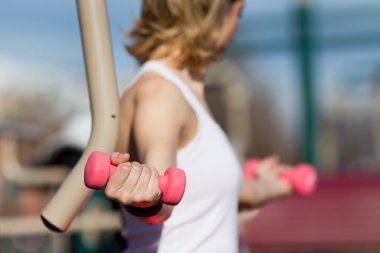 Dambıllarla egzersiz yapan kız.