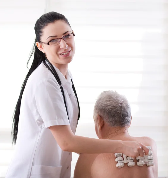 Nurse masagging old man with roller massager — Stock Photo, Image