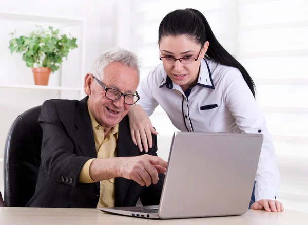 Старший мужчина и молодая женщина, глядя на ноутбук — стоковое фото