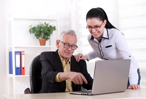 Hombre mayor y mujer joven mirando portátil — Foto de Stock