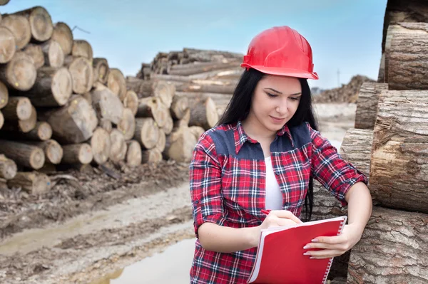 Vrouwelijke bos ingenieur naast logboeken — Stockfoto
