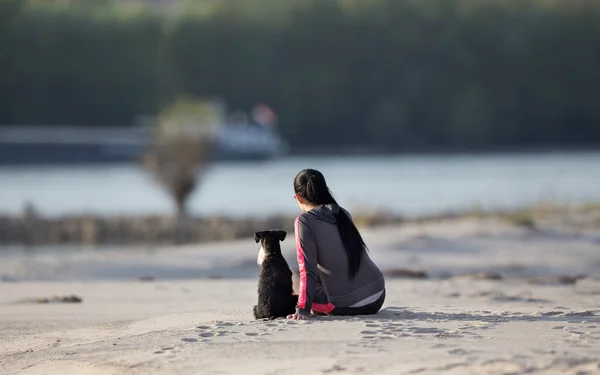 Chica con perro en la costa arenosa — Foto de Stock