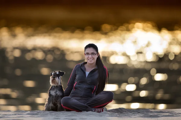 Дівчина з собакою на піщаному узбережжі — стокове фото