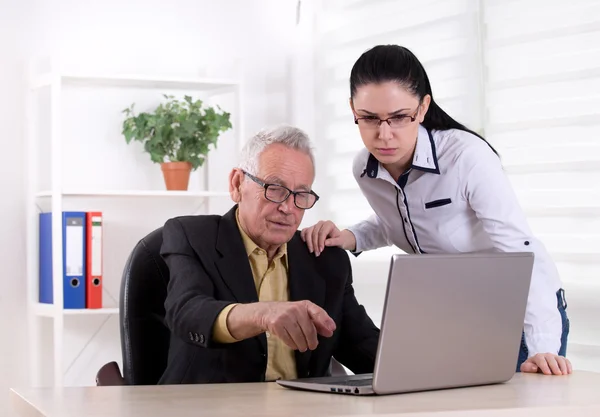 Äldre man och ung kvinna tittar på laptop — Stockfoto