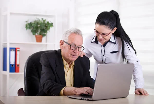 Homme âgé et jeune femme regardant ordinateur portable — Photo