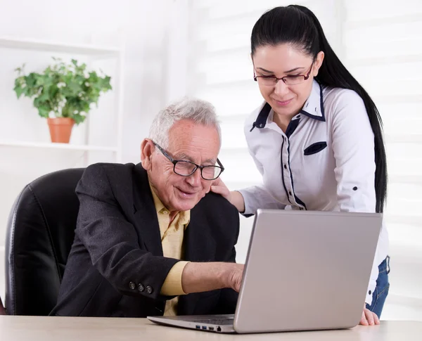 Homem sênior e mulher jovem olhando para laptop — Fotografia de Stock