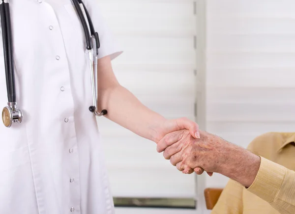 Krankenschwester und Senior beim Händeschütteln — Stockfoto