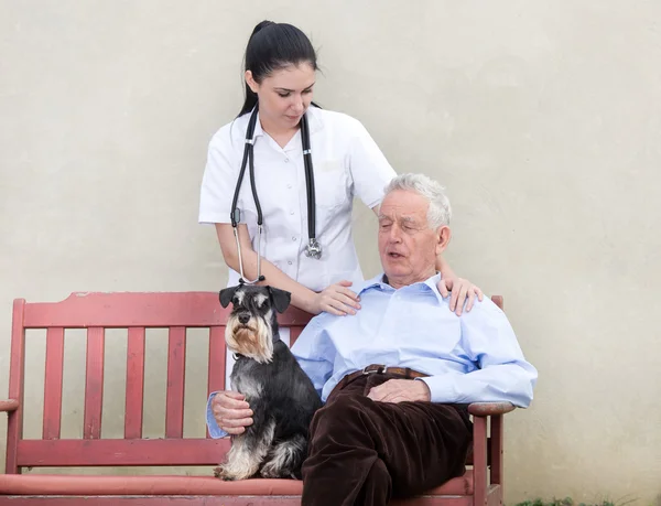 Äldre man med vårdgivare och hund — Stockfoto