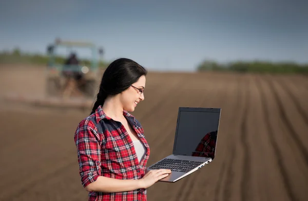 Boer meisje met laptop in het veld — Stockfoto