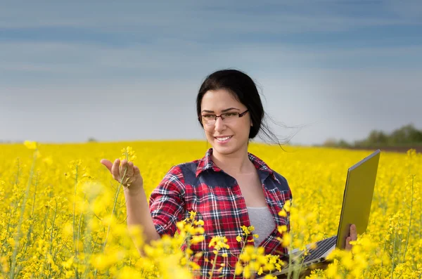 Bäuerin mit Laptop im Rapsfeld — Stockfoto