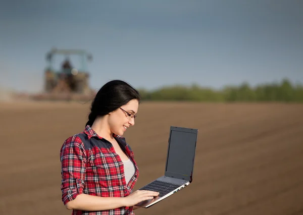 Boer meisje met laptop in het veld — Stockfoto