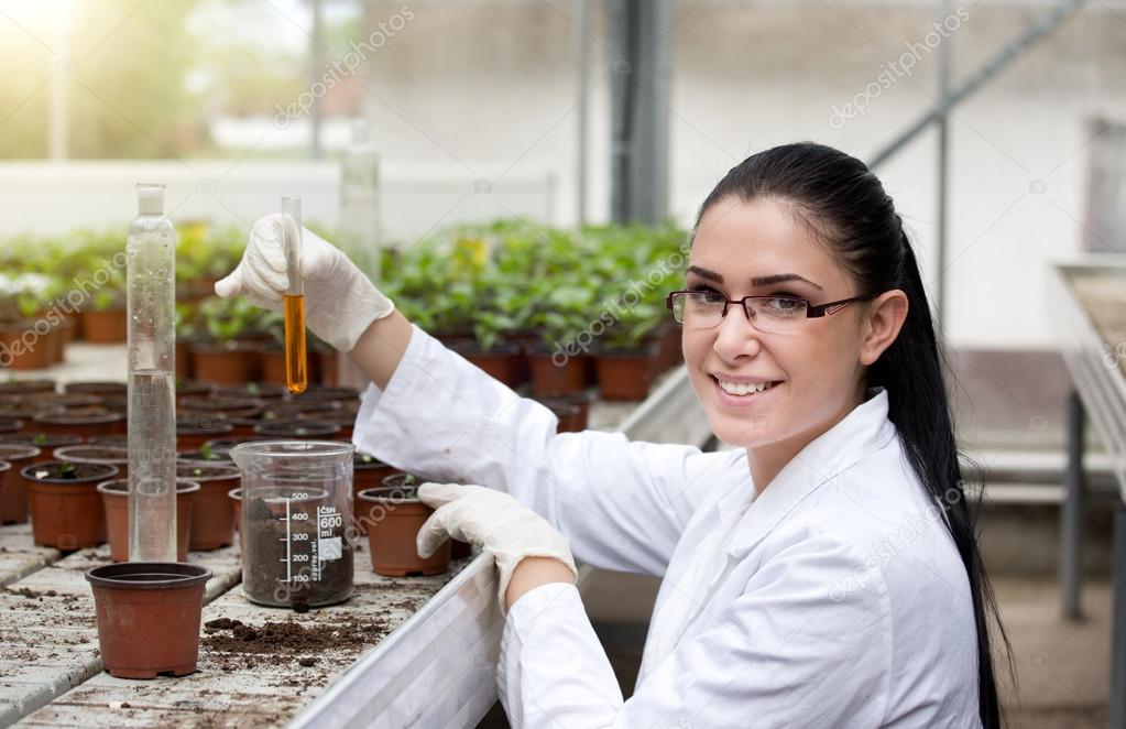 Biloist holding test tube in greenhouse