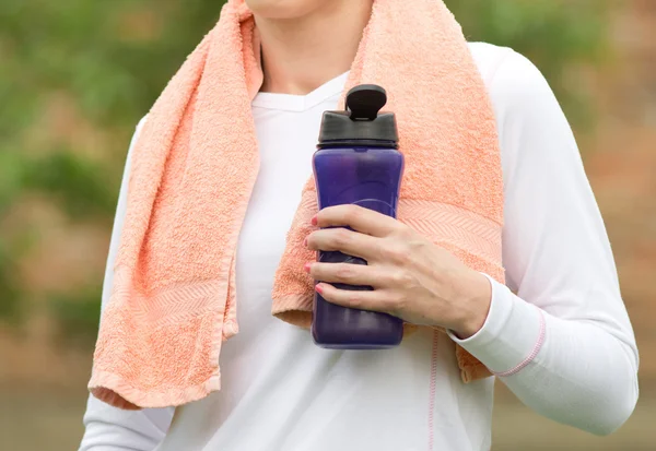 Deportiva con botella descansando en el parque — Foto de Stock