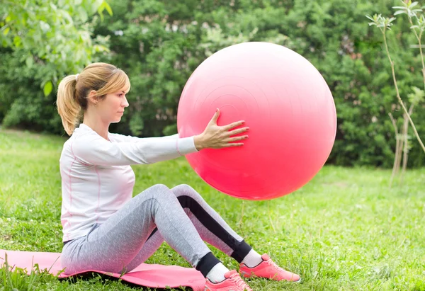 Chica elevación fitball en el jardín — Foto de Stock