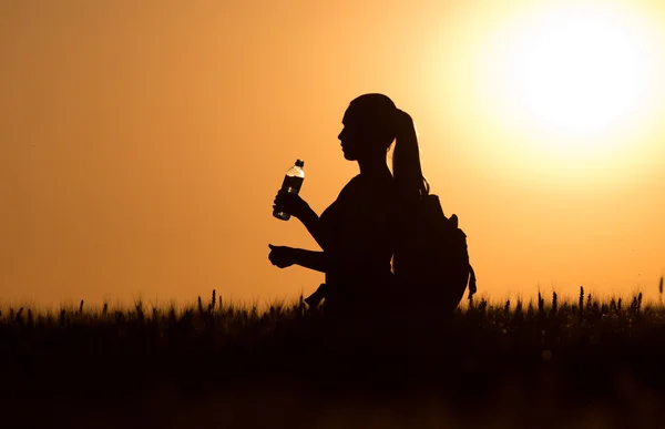 Silhouet van de vrouw met rugzak en fles water — Stockfoto