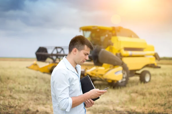 Businessman with laptop and cell phone in front of combine harve — Stock Photo, Image