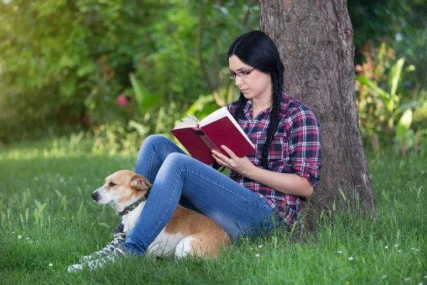 Mädchen mit Hund im Gras, liest ein Buch — Stockfoto