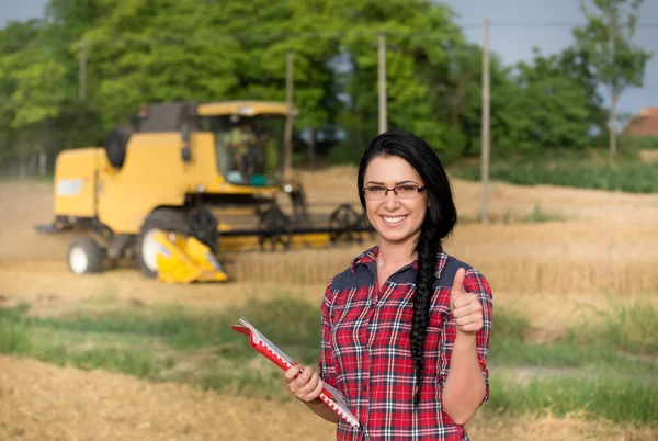 Jordbrukaren flicka på fältet med skördetröska — Stockfoto