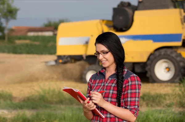 Agricoltore ragazza sul campo con mietitrice — Foto Stock