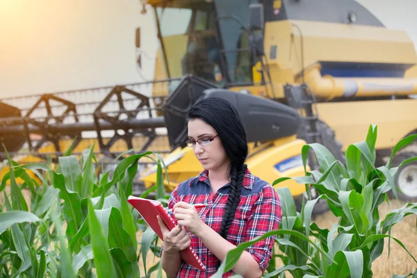 Chica agricultor en el campo con cosechadora — Foto de Stock