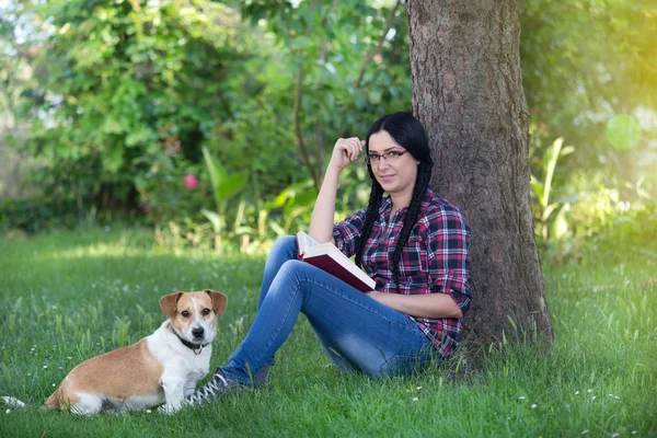 Dziewczyna z psem na trawie, czytanie książki — Zdjęcie stockowe