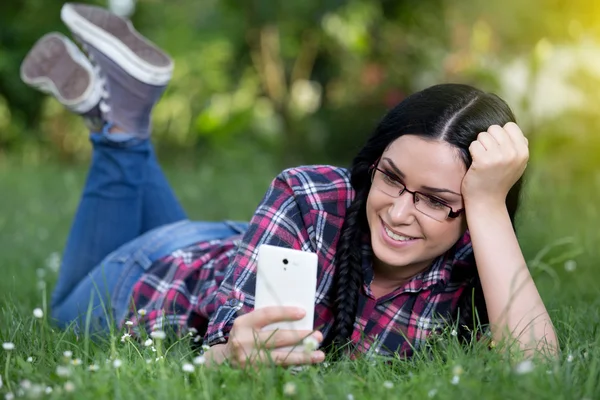 Girl texting on smart phone on grass — Stock Photo, Image