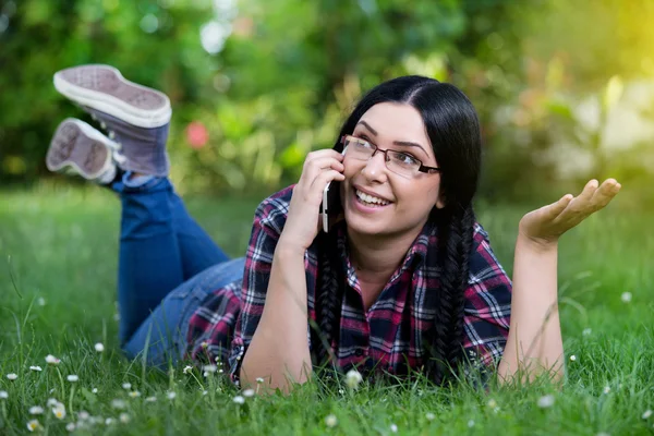 Девушка разговаривает по телефону на траве — стоковое фото