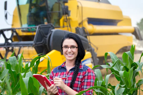 Farmer girl on field with combine harvester — Stock Photo, Image