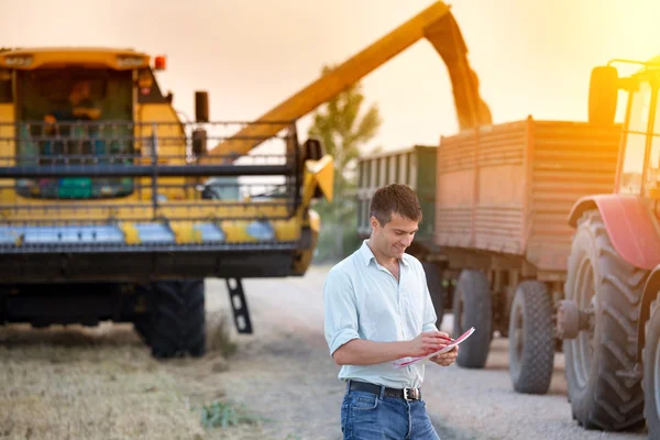 Farmer with agricultural machinery on harvest — Stock Photo, Image