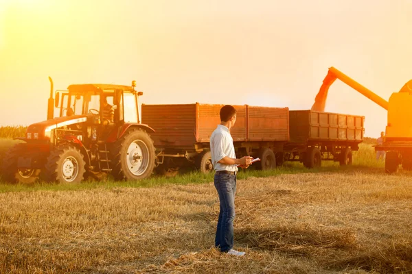 Farmer with agricultural machinery on harvest — Stock Photo, Image